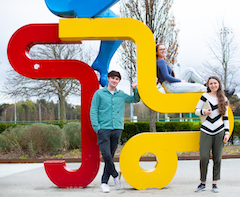 students posing next to UCD sports centre sculpture